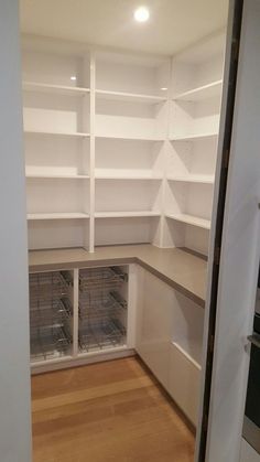 an empty kitchen with white shelving and wood flooring in the middle of it