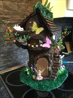 a bird house made out of fake grass and flowers on top of a stovetop