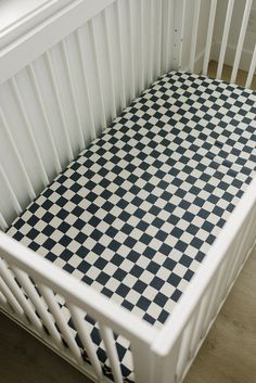 a white crib with black and white checkered sheets