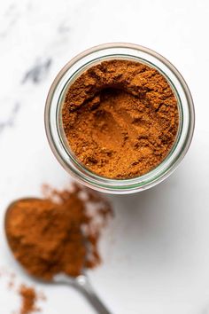 a glass jar filled with brown powder next to a spoon