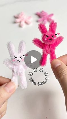 two small stuffed animals being held up by someone's hands with pink and white bunny ears