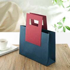 a blue and red bag sitting on top of a wooden table next to a cup