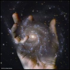 a person holding their hand up in front of a spirally shaped object with stars all around it