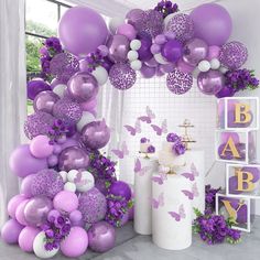 purple and white balloons are hanging from the ceiling in front of a baby's room