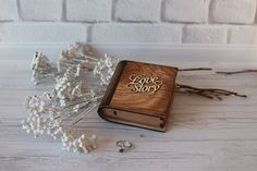 a wooden book with the word love story written on it next to some dried flowers