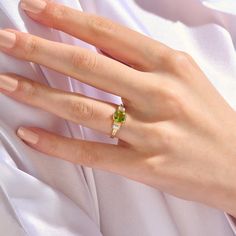 a woman's hand wearing a gold ring with a green gemstone on it