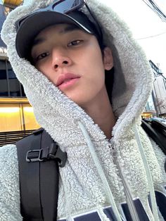 a young man wearing sunglasses and a hoodie is standing in front of a building