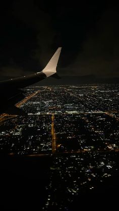 an airplane wing flying over the city at night