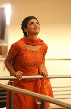 a woman in an orange dress standing on a railing