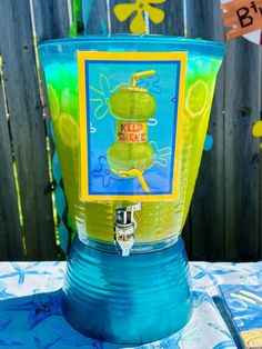 a blue and yellow blender sitting on top of a table next to a fence