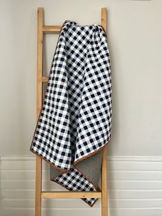 a black and white checkered blanket sitting on top of a wooden chair next to a wall