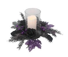 a candle and some flowers on a white surface with purple leaves in the center,