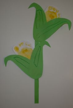 a paper cutout of two flowers on a white wall with green stems and yellow centers