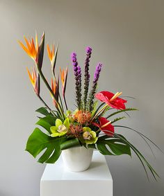 a white vase filled with lots of colorful flowers