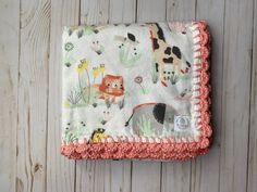 a baby blanket with animals on it sitting on top of a wooden floor next to a wall