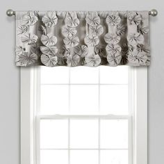 a window with a white curtain and flowered valance in front of the window