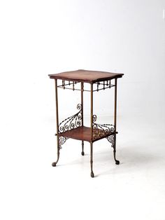 a small wooden table with wrought iron work on it's legs and shelf underneath