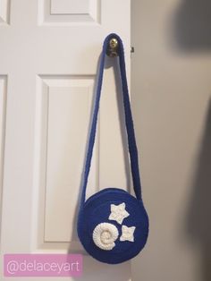 a blue purse hanging on the front door with white stars and pearls attached to it