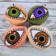 three handmade pillows with painted eyes on them sitting on a wooden table next to each other