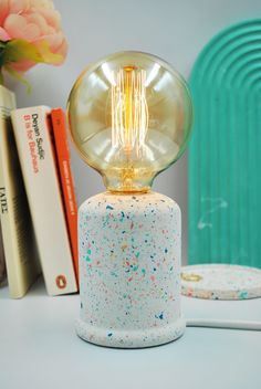 a table with a lamp on top of it next to some books and a vase