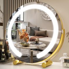 a round mirror sitting on top of a table next to a white couch and coffee table