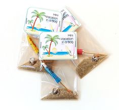 three small plastic bags filled with different types of sand and some writing materials in them