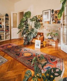 a living room filled with lots of furniture and plants on top of a wooden floor