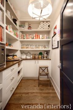 a kitchen with white cupboards and shelves filled with various items on top of them