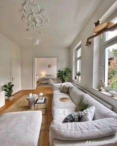 a living room filled with white furniture and lots of windows