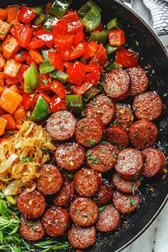 a skillet filled with sausage, peppers and onions