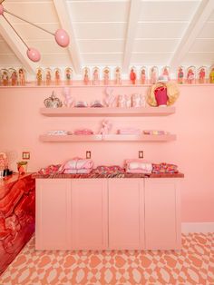 a room with pink walls and shelves filled with doll accessories on top of them,