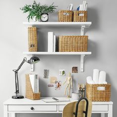 a white desk with wicker baskets on the shelves and a chair in front of it