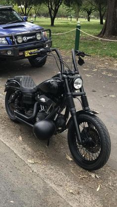 a motorcycle parked on the side of a road next to a blue pick up truck