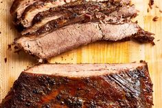 sliced meat sitting on top of a cutting board next to another piece of meat that has been cut in half