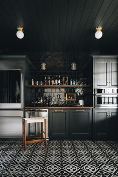 a kitchen with black and white tiles on the floor, dark cabinets and counter tops