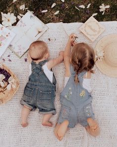 two toddlers are playing on a blanket