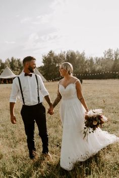 a bride and groom holding hands in a field