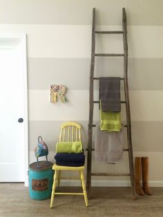 a ladder leaning up against a wall next to a yellow chair and green towel rack