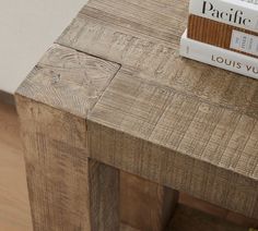 a wooden table with a book on top of it next to a white wall and wood floor