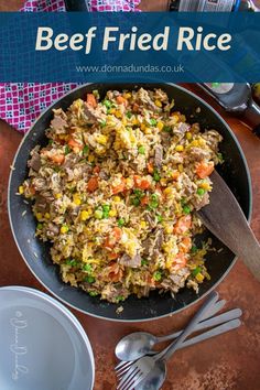 beef fried rice in a skillet with spoons on the side and fork next to it