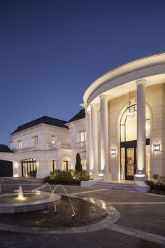 a large white building with a fountain in front of it at night, lit up by lights