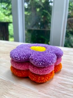 four crocheted flowers sitting on top of a wooden table next to a window