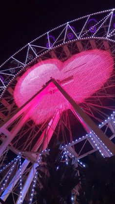 the ferris wheel is lit up with pink lights