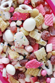 a pink bowl filled with lots of different types of candy and marshmallows