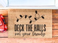 a door mat with the words deck the hall not your family on it next to red shoes