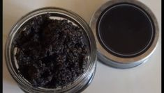 a jar filled with black stuff sitting on top of a white counter next to a cup