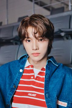 a young man with brown hair wearing a red and white striped shirt, blue denim jacket and jeans