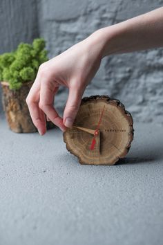 a person is reaching for a piece of wood with a clock on it