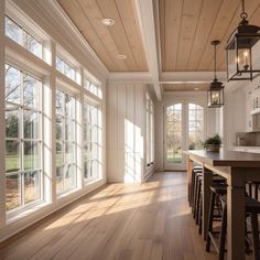 an empty kitchen with wood floors and large windows on the wall, along with bar stools