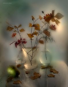 a vase filled with flowers and leaves on top of a table